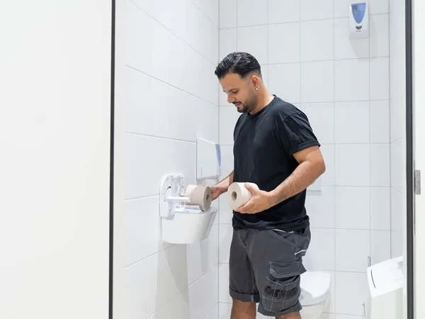 Servicemedewerker vult duurzaam wcpapier aan in duo toiletrolhouder
